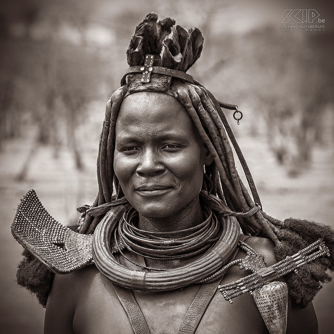 Omangete - Himba vrouw Een van de oudere Himba vrouwen van het dorp was blijkbaar ook een van de leiders. De Himba vrouwen zijn beroemd voor het insmeren van hun haar en lichaam met otjize (mengsel van vet en oker). Getrouwde Himba vrouwen dragen hoofdtooien met gevlochten haar en een soort tulband gemaakt van geitenleer en kettingen versierd met schelpen en sieraden gemaakt van ijzer en koper. Stefan Cruysberghs